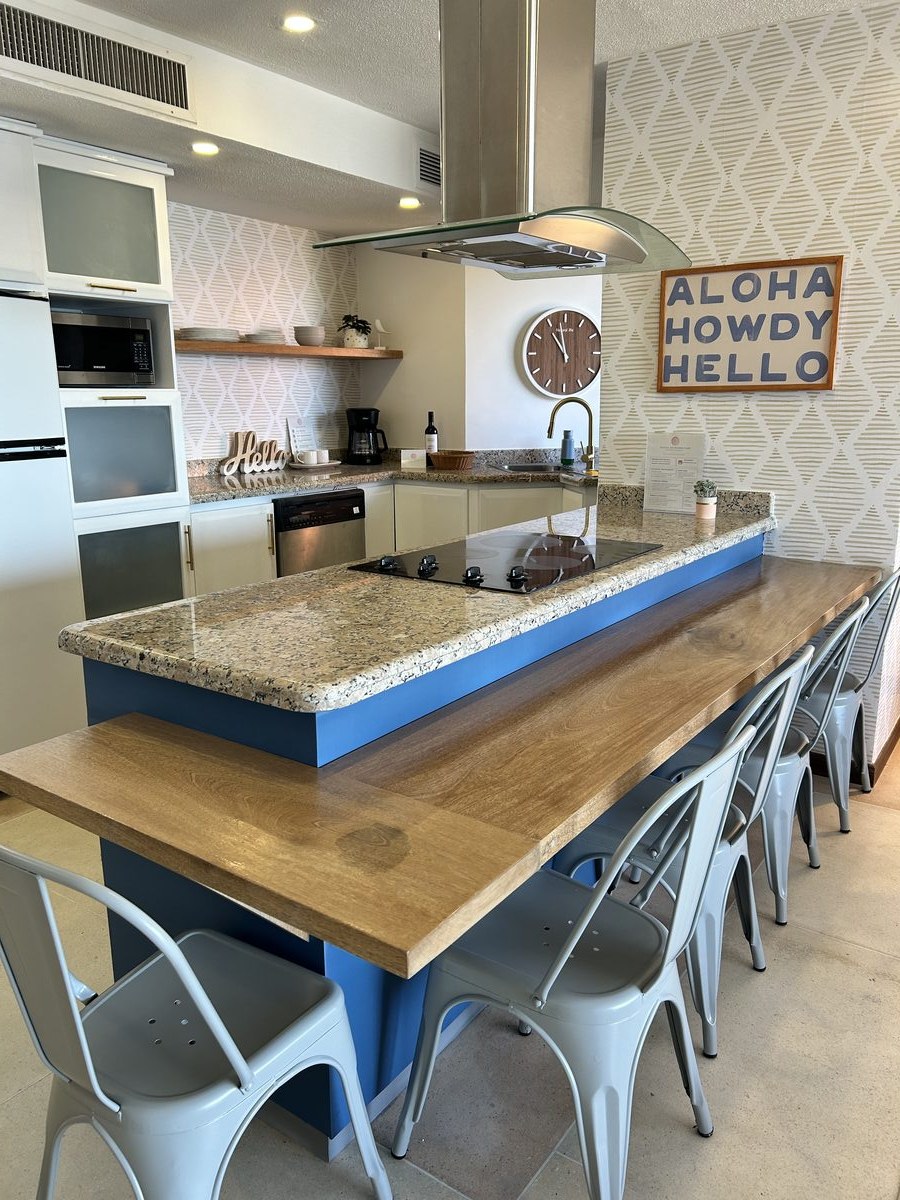 Beach condo kitchen with a blue island, live-edge breakfast bar and seating for six guests