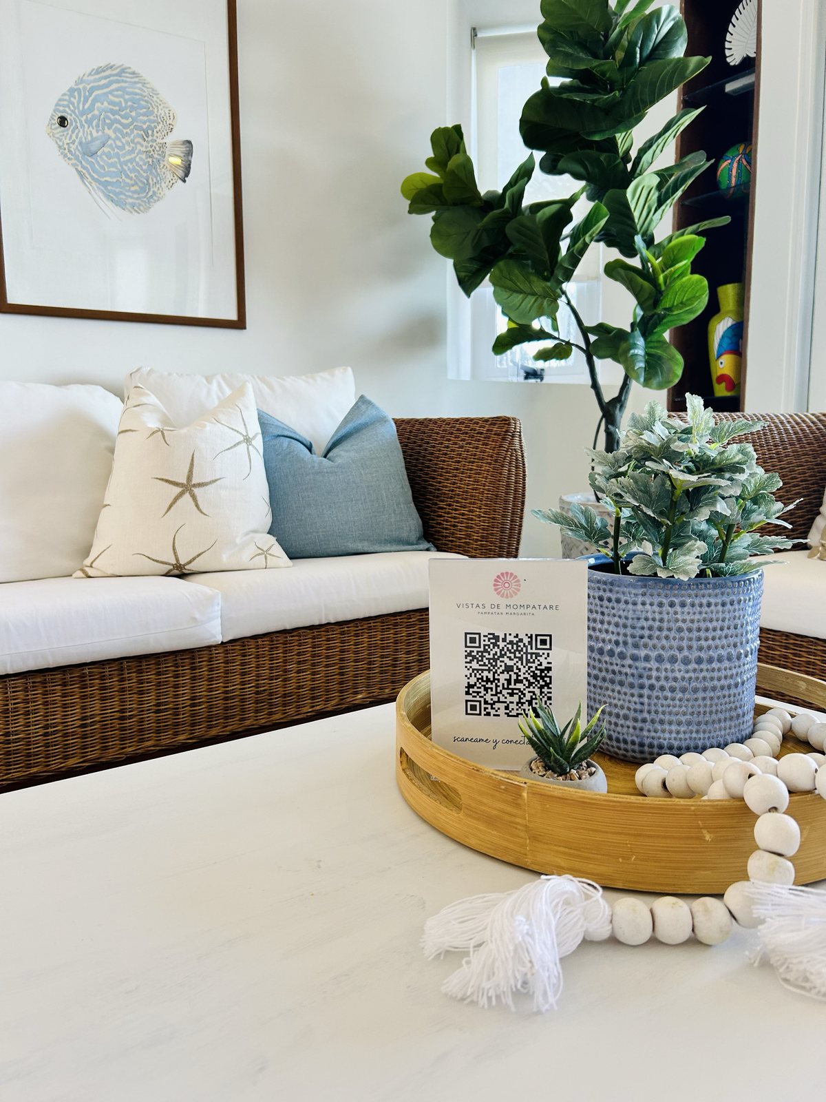 Coffee table styling detail with framed fish print and rattan seating