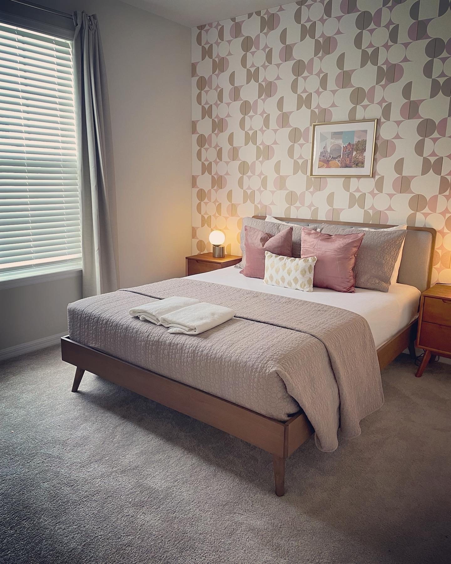 Mid-century guest bedroom with geometric wallpaper and blush bedding