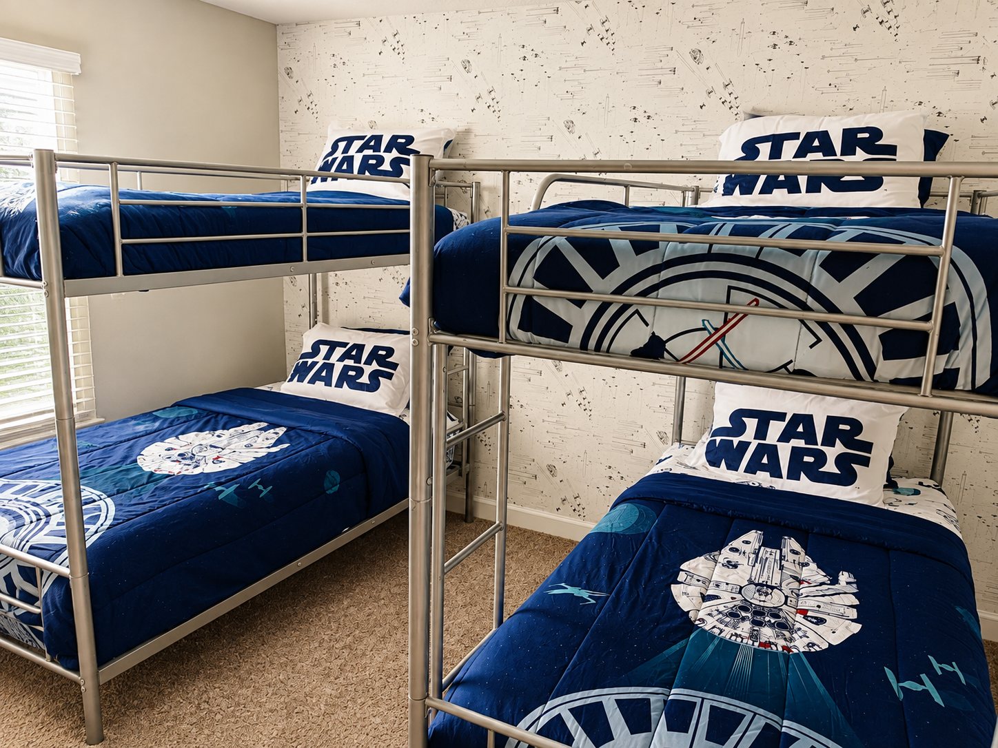 Two sets of twin bunk beds with patterned wallpaper and themed bedding