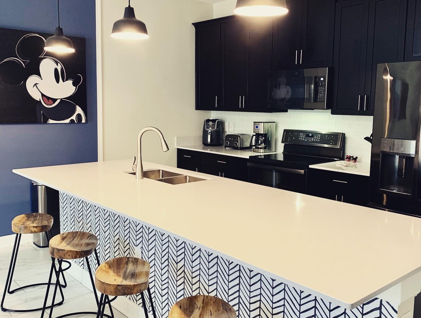 Kitchen with black cabinetry, quartz island and herringbone panelled bar front
