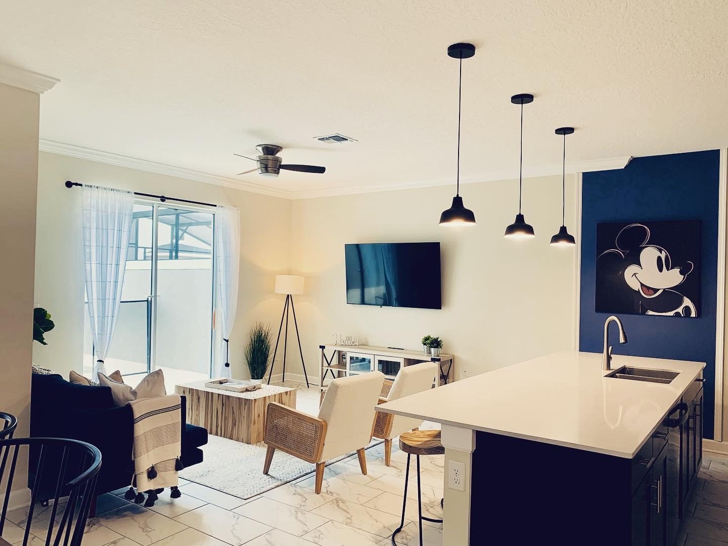 Open-plan living area with navy feature wall, cane armchairs and kitchen island